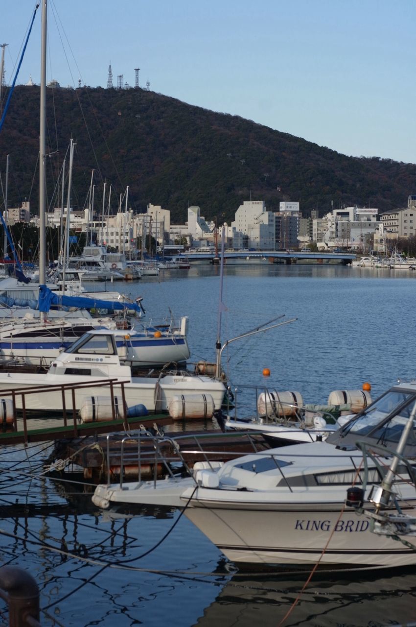 nautical vessel, moored, water, boat, transportation, mode of transport, harbor, sea, clear sky, built structure, building exterior, mast, mountain, blue, sailboat, architecture, sky, day, outdoors, marina