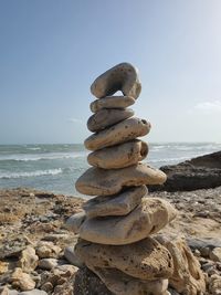 Stack of stones on beach against sky
