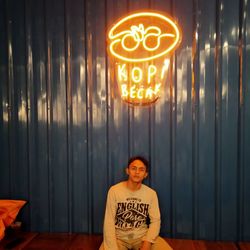 Portrait of smiling man standing against illuminated wall