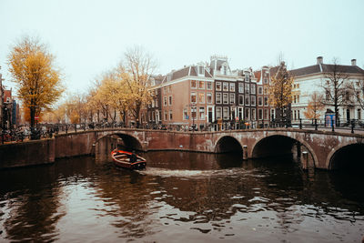 Bridge over canal in city against clear sky