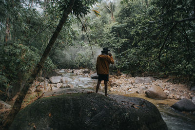 Rear view of man walking on rocks in forest