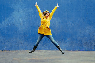 Full length of woman jumping against wall