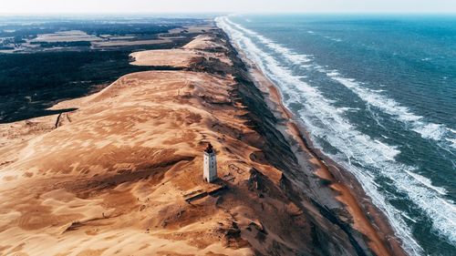 High angle view of lighthouse on hill by sea