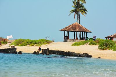 Lounge chairs by swimming pool in sea against clear sky