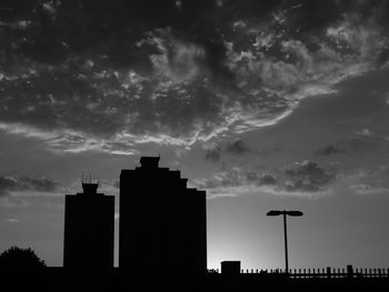 Silhouette of city against cloudy sky