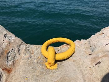 High angle view of yellow container on rock by sea