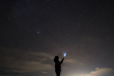 Low angle view of silhouette man standing against star field at night