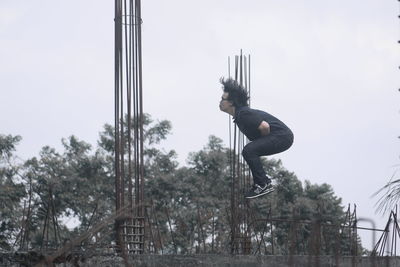 Low angle view of man jumping against sky