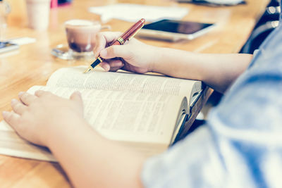 Midsection of woman reading book on table