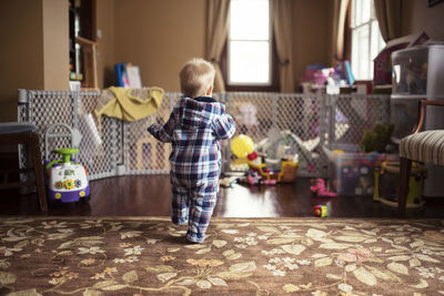 Rear view of baby boy walking on floor at home