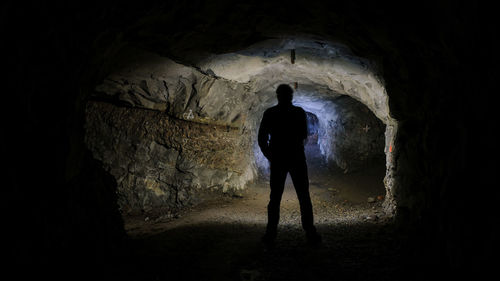Rear view of silhouette man standing in cave