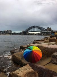 Multi colored umbrella on bridge over sea against sky