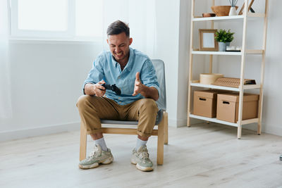 Portrait of young man sitting on chair at home