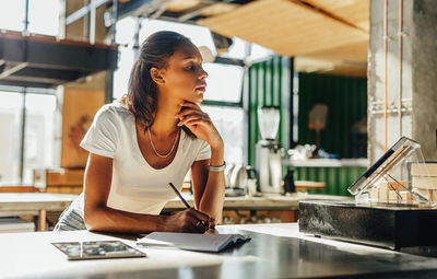 Young woman using mobile phone while standing on table