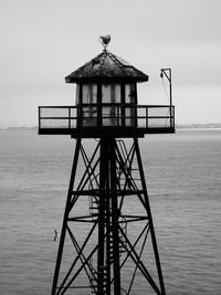 Traditional windmill by sea against sky