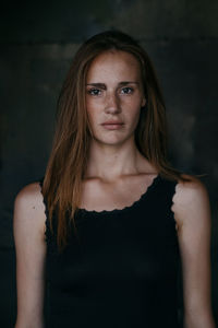 Portrait of young woman standing against wall