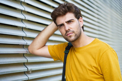 Close-up of young man looking away while standing by wall outdoor