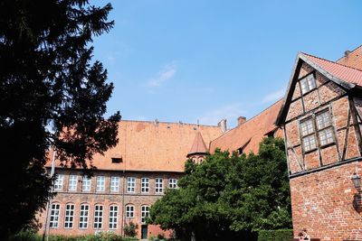 Low angle view of trees and building against sky
