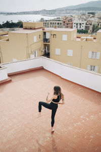 High angle view of woman practicing kicks on building terrace