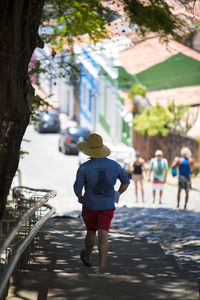 Rear view of people walking on footpath in city