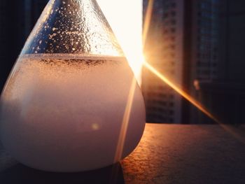 Close-up of glass bottle against building on sunny day