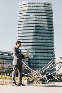 Full length of young man standing on mobile phone in city
