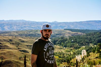 Portrait of young man standing on landscape against sky