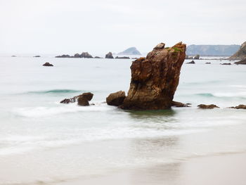 Rock formation on beach against sky