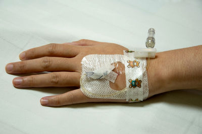 Cropped hand of patient wearing iv drip in hospital