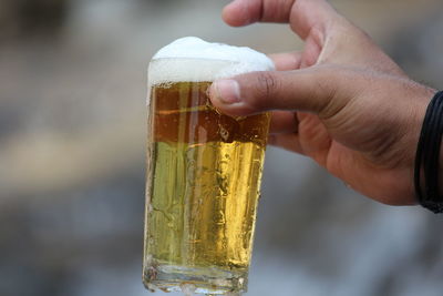Close-up of hand holding beer glass