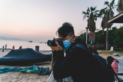 Woman photographing at beach against sky