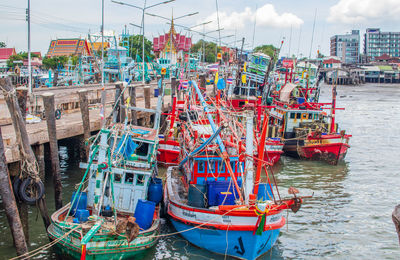 Fishing boats moored at harbor against sky