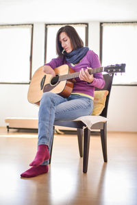 Full length of woman with disability playing guitar