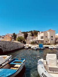 Boats in sea against clear blue sky