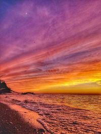 Scenic view of sea against dramatic sky during sunset