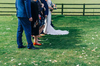 Low section of couples standing on grass