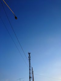 Low angle view of electricity pylon against blue sky