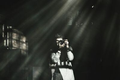 Sunlight falling on man photographing in darkroom