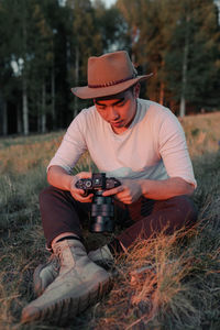 Midsection of man holding hat on field