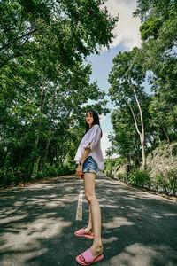 Full length of woman standing on road against trees