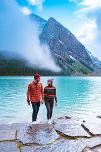 Rear view of men standing on lake against sky