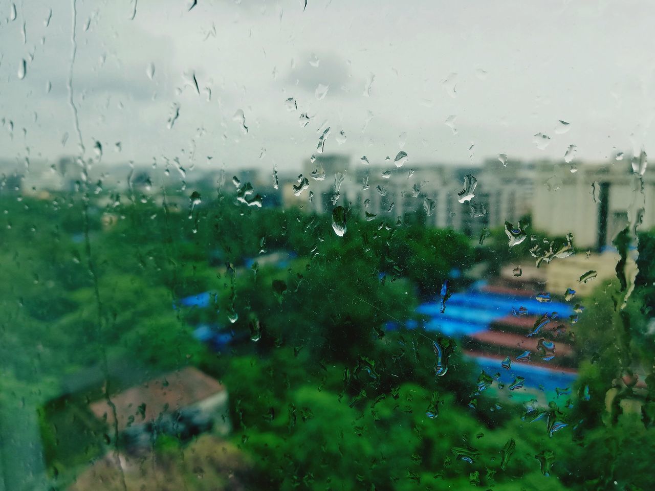 RAINDROPS ON GLASS WINDOW AGAINST SKY