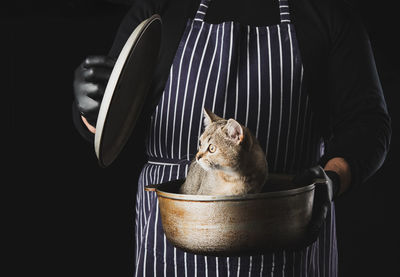 Man chef in a striped blue apron holds an aluminum cauldron in his hand, a cute funny scottish str