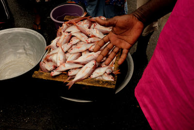 Midsection of person buying fishes in market