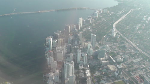 Aerial view of city by sea against sky