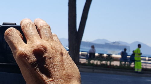 Close-up of man hand against sky