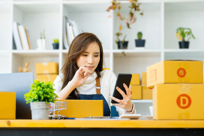 Young woman using mobile phone while sitting at home