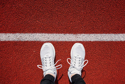 Top view of white male running sneakers near start line at stadium track