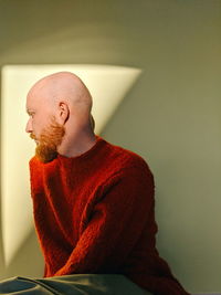 Young man looking away against wall