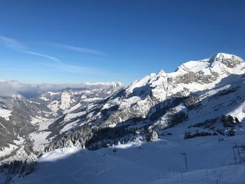 Scenic view of snowcapped mountains against blue sky